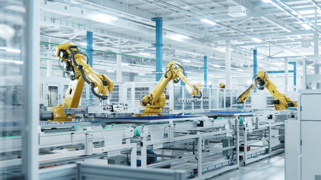 Zrobotyzowane gniazdo produkcyjne z ramieniem robota przemysłowego na hali produkcyjnej.